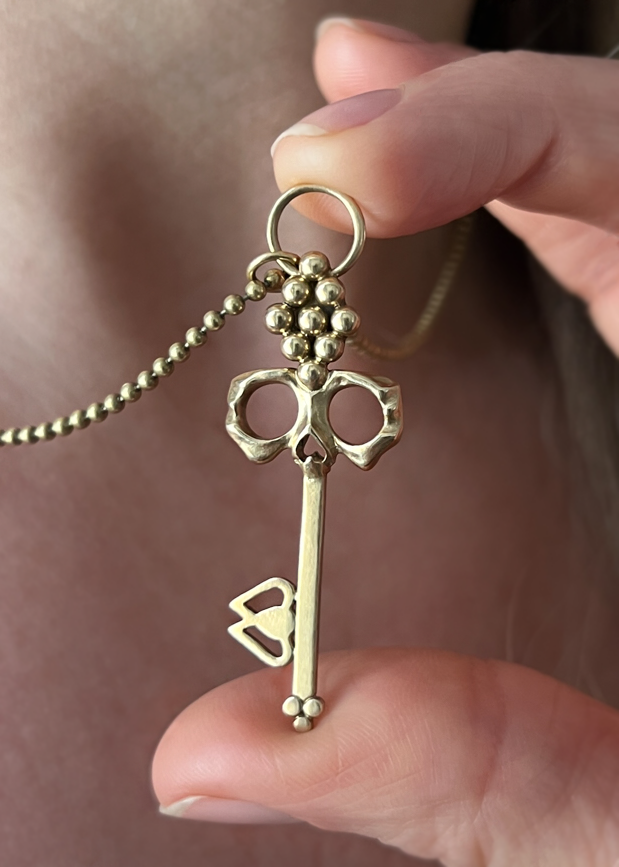 Brass Skull Key Necklace held in hand