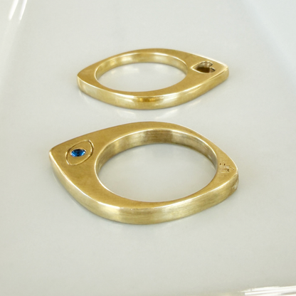 Brass Evil Eye Slice ring with blue stone
laying flat on jewelry dish