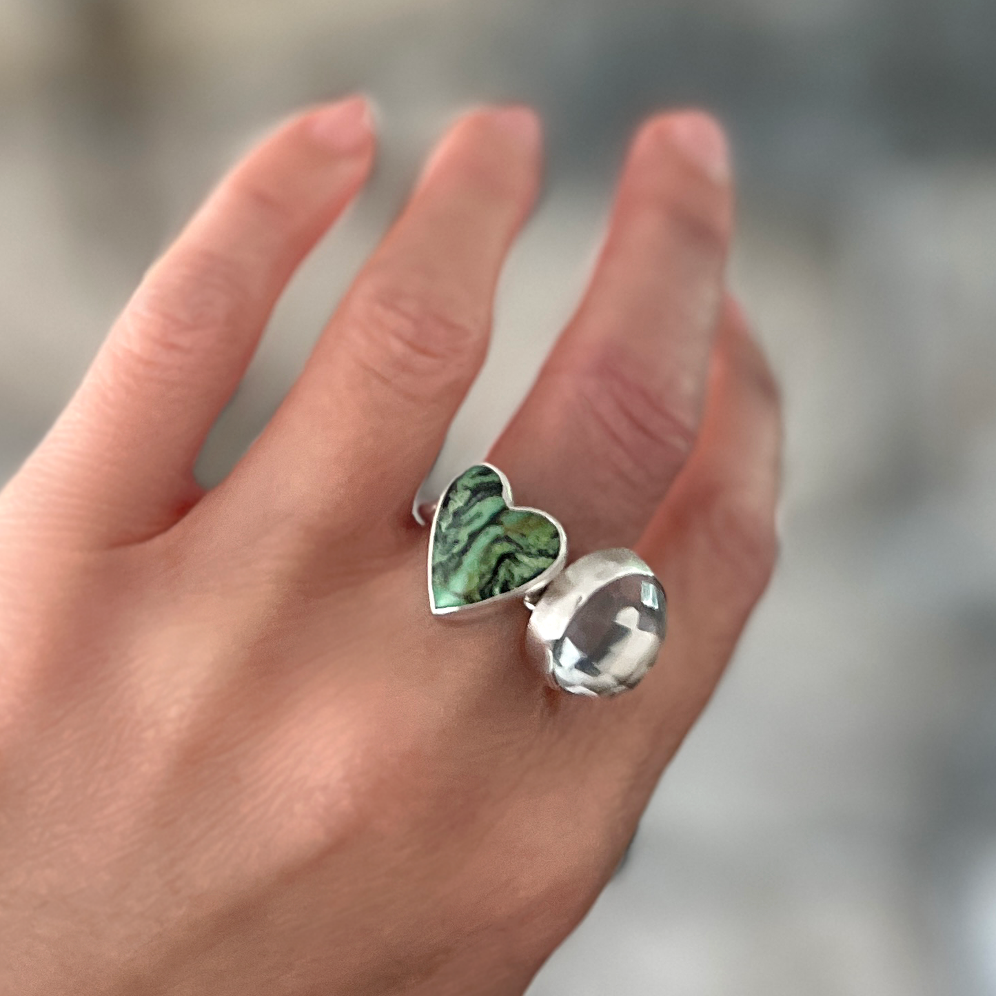 Green turquoise heart and sterling silver ring stacked with another ring on hand