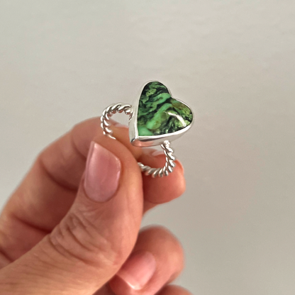 Green Turquoise Heart and sterling silver ring held in fingers.