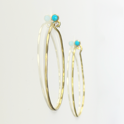 Golden, hammered hoop earrings with turquoise stones on a white background