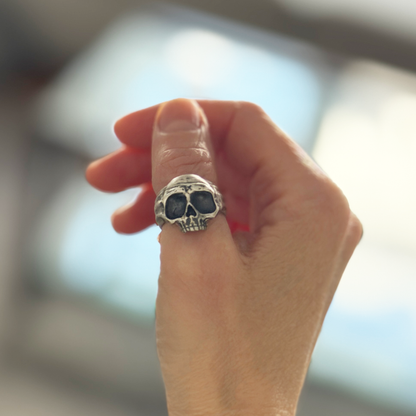 Hand wearing a skull-shaped ring with a blurred background