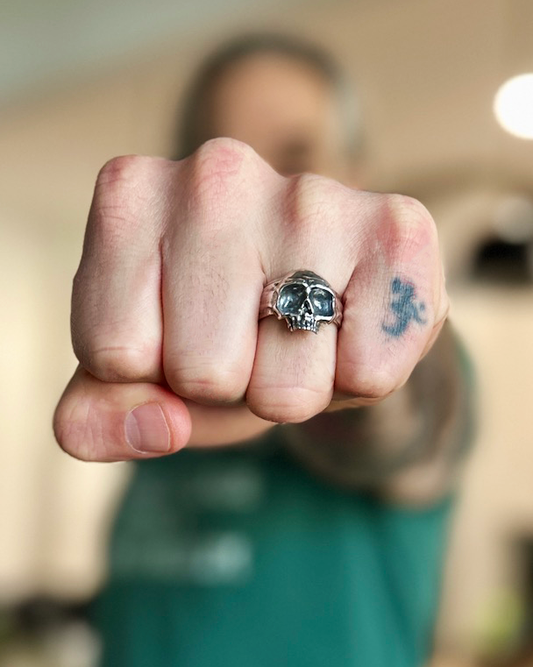 Hand wearing a skull ring with a blurred background