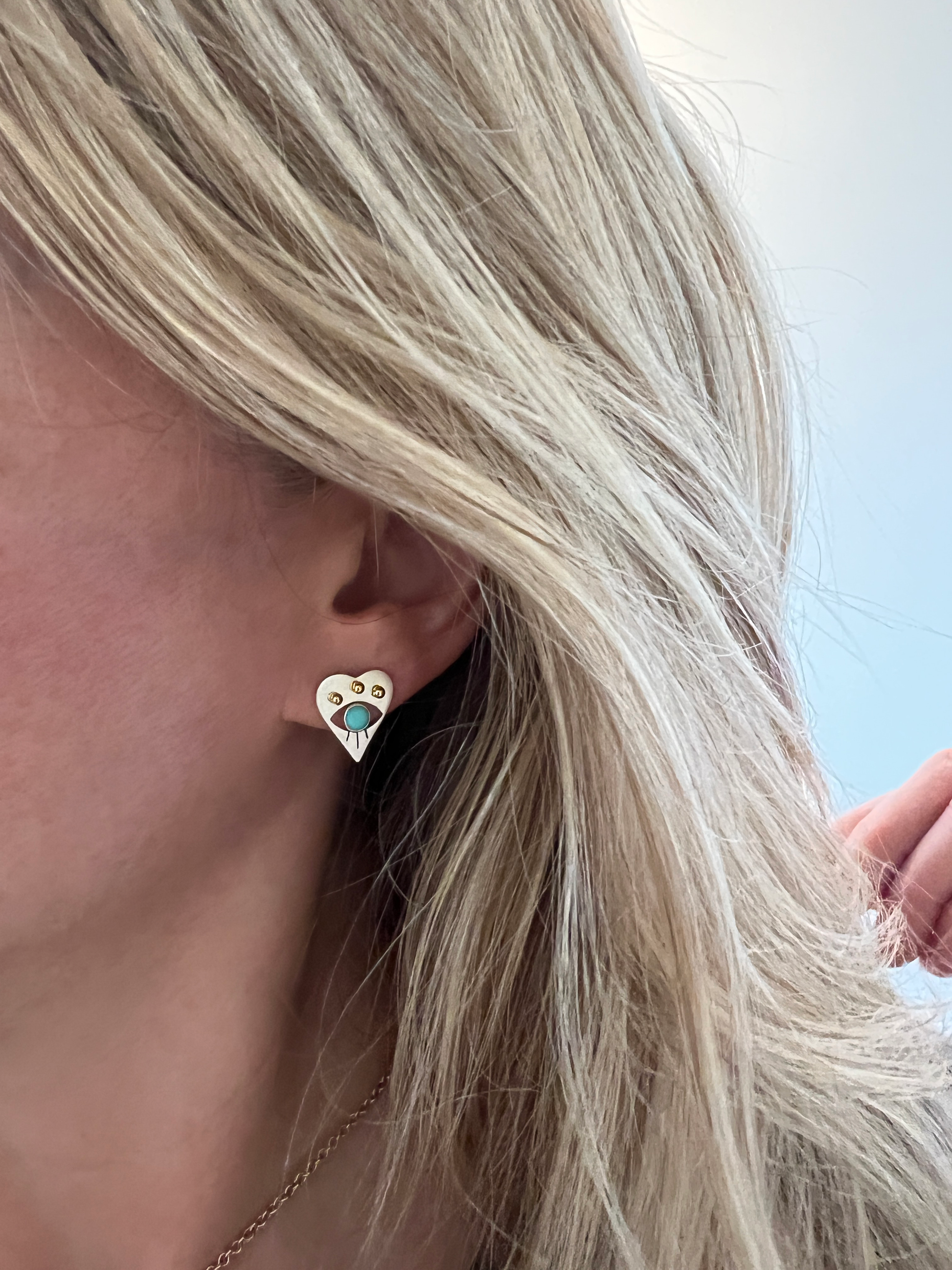 Sterling and turquoise evil eye heart stud earring being worn 