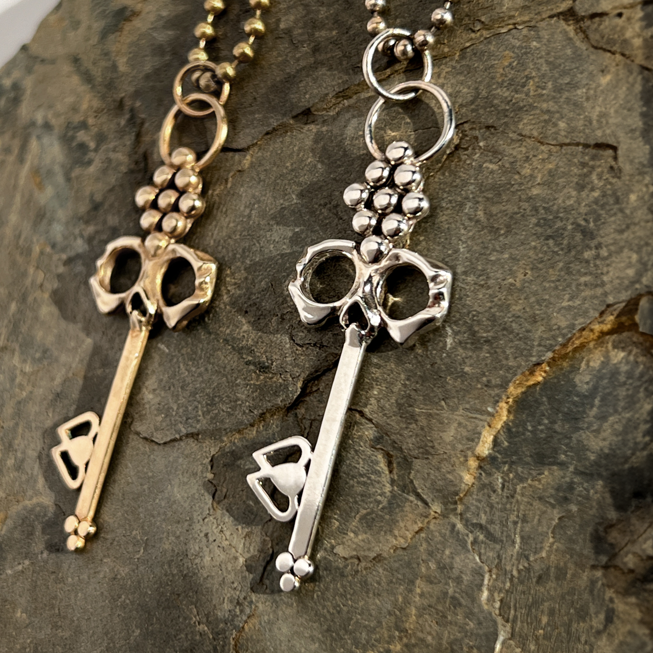 Men's Sterling Silver Skull Key Necklace on durable ball chain shown on natural rock with Brass option