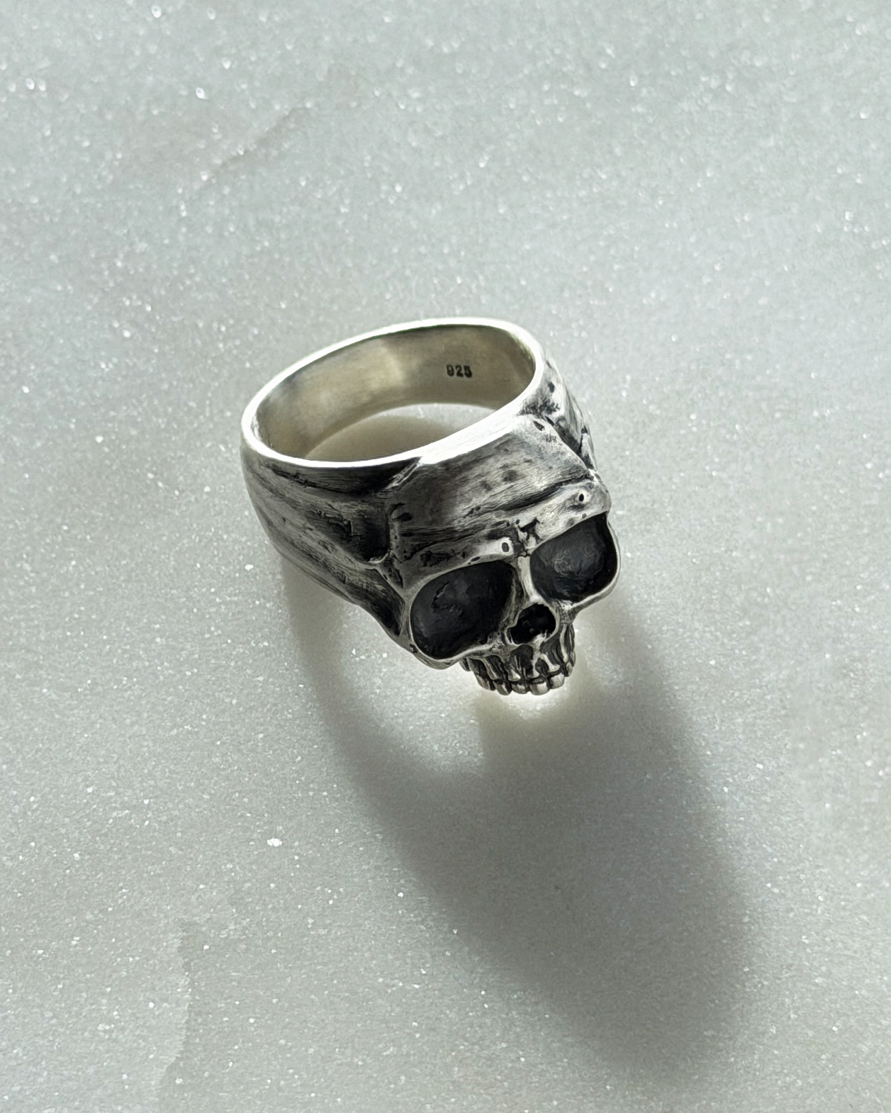 Silver skull ring on a light gray background